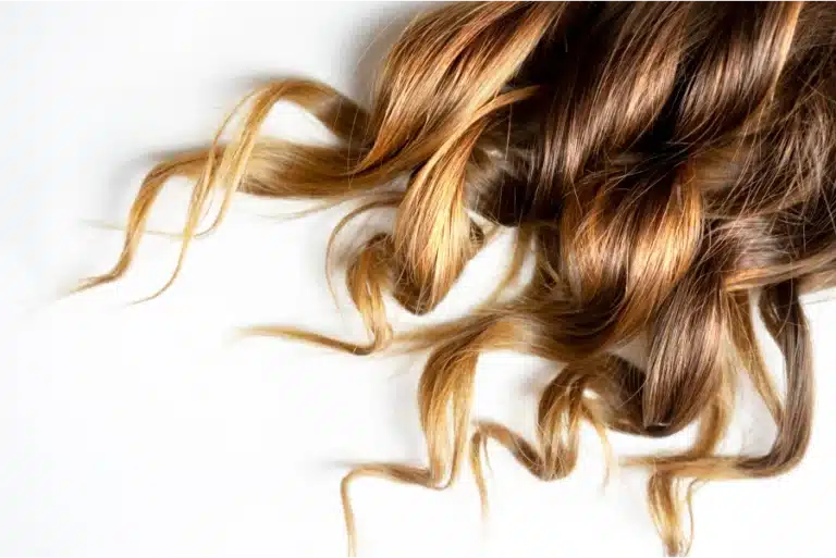 Wavy brown and blonde highlighted hair against a white background.