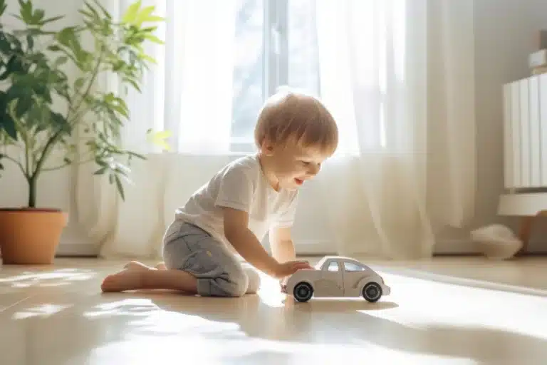 Toddler playing with a toy car on a sunlit floor in a bright, cozy room.