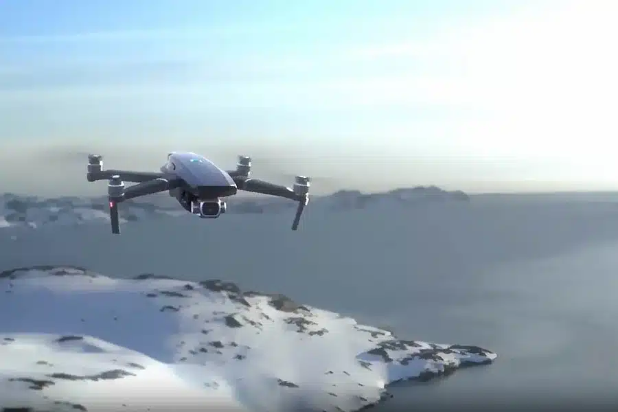 Drone flying over snowy mountains and icy cliffs.