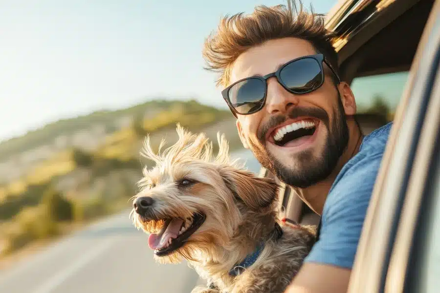 Man and dog enjoying a road trip with their heads out the car window.