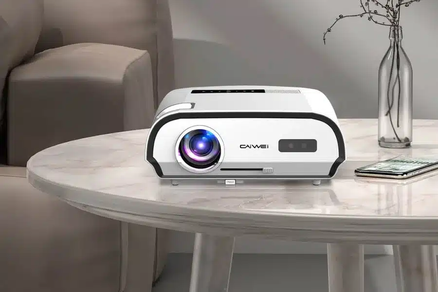 Sleek white projector on a round wooden table in a stylish living room.