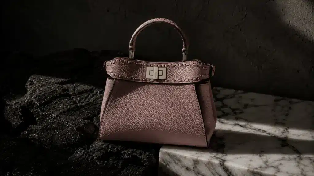 Fendi Peekaboo bag in dusty rose leather on marble, representing eco-friendly luxury brands with artisanal craftsmanship.
